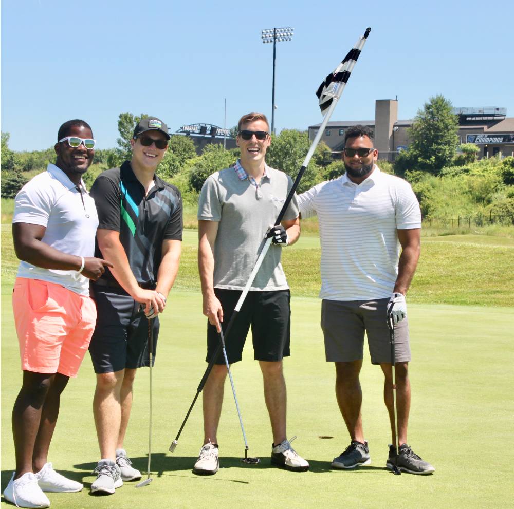 football alumni hold golf flag before they get their ball